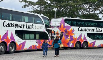 A-muslim-mother-hold--her-kid's-hand-in-front-of-Casuseway-Link-high-deck-bus-for-CSR-program