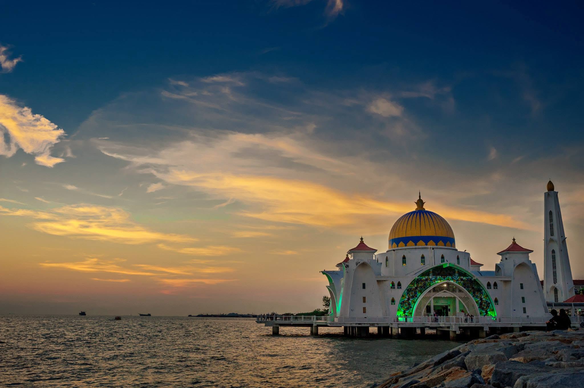 Melaka Straits Mosque silhouetted against a golden sunset over the water