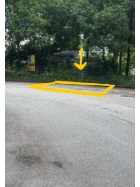 The kerbside coach bay, outlined in yellow on the road surface, with a yellow arrow pointing down to the waiting spot.